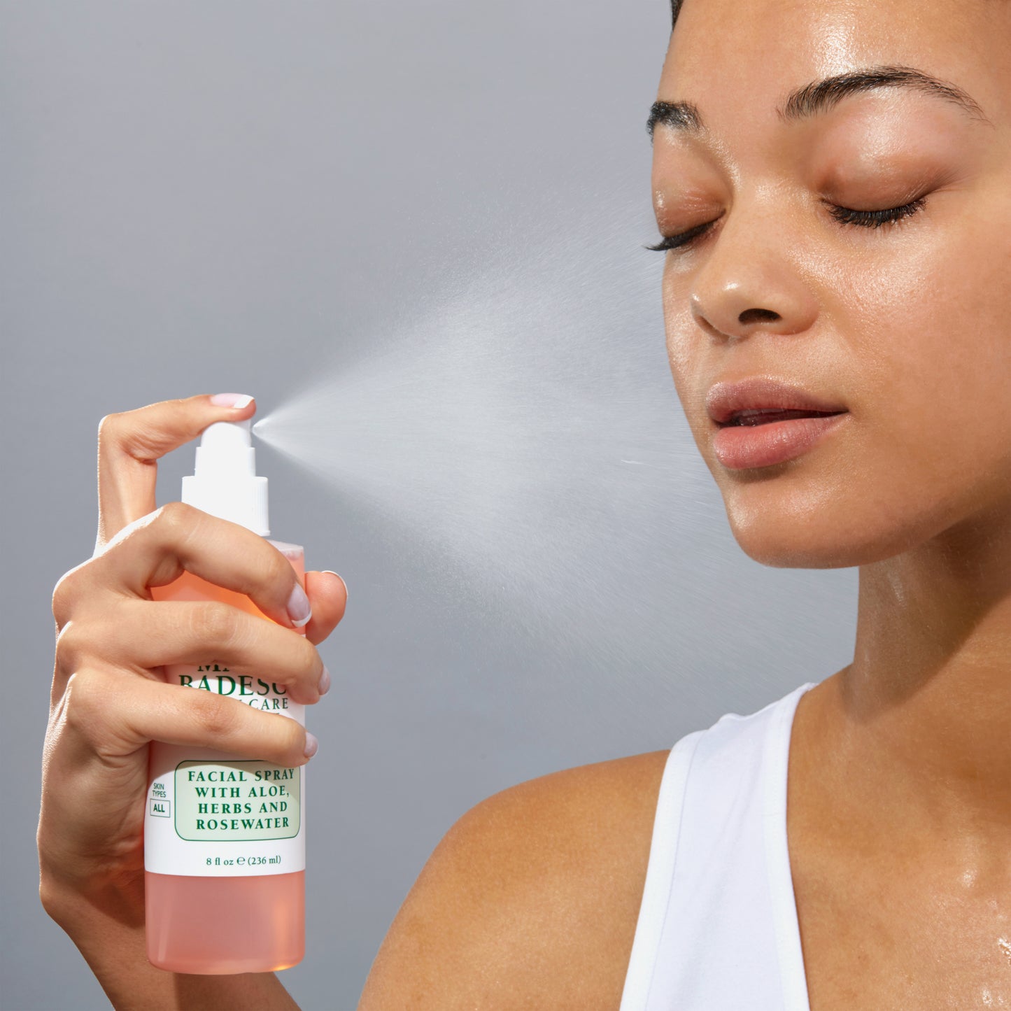 Woman misting with glowing skin Facial Spray With Aloe, Herbs, Rosewater onto her face