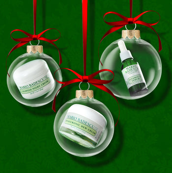 Mario Badescu skincare products in Christmas ornament packaging on a green background