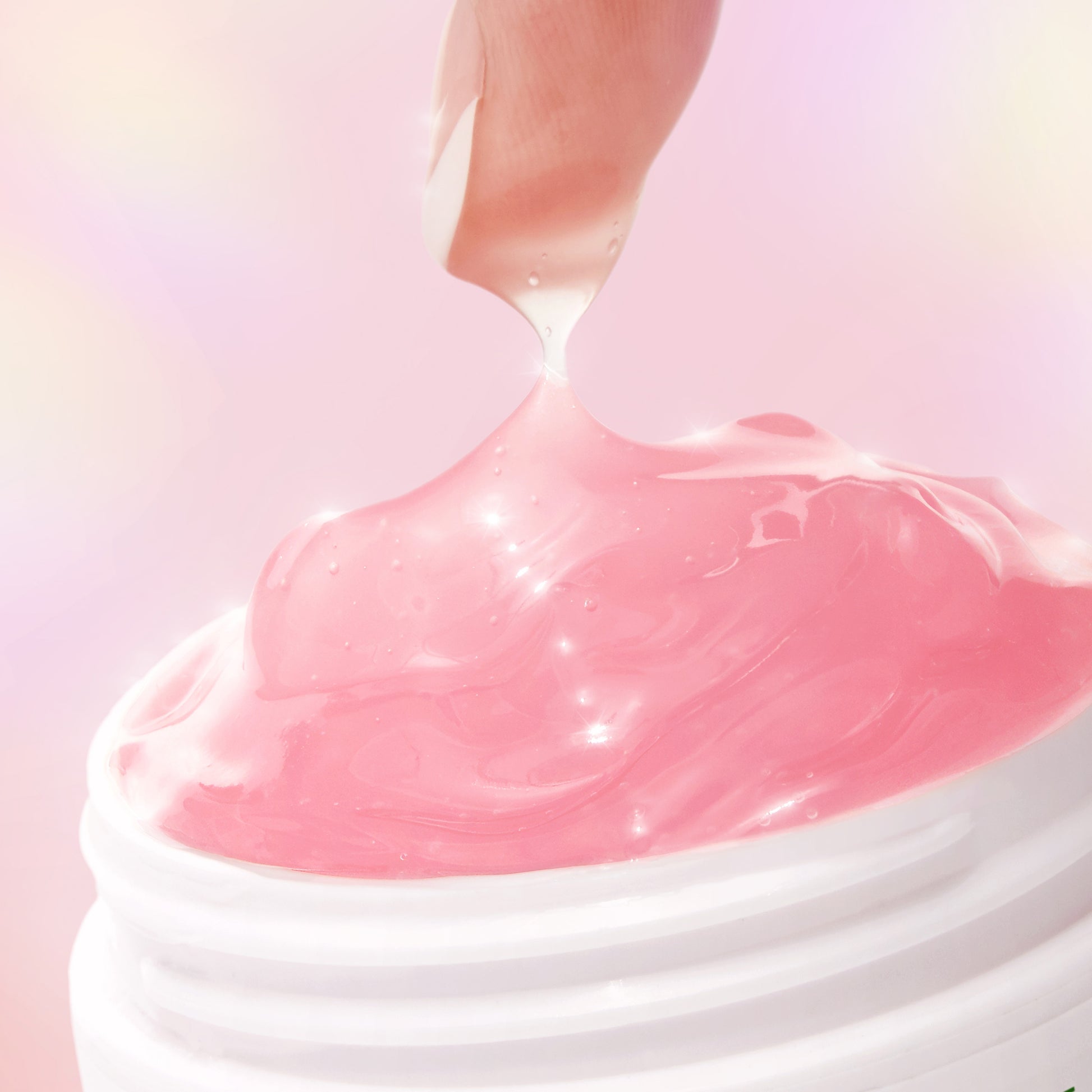 Pink cream being squeezed out of a white container on a pink background