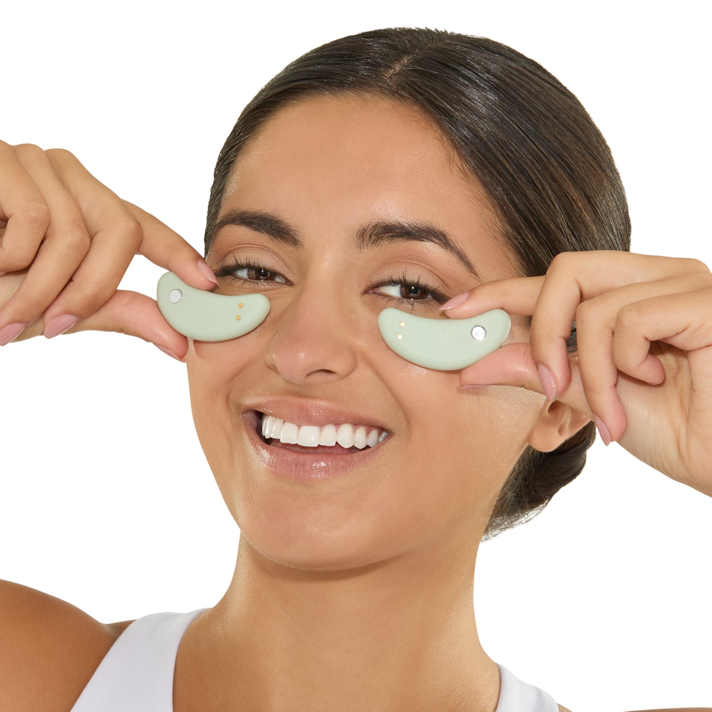 Woman applying green eye patches to her eyes on a white background