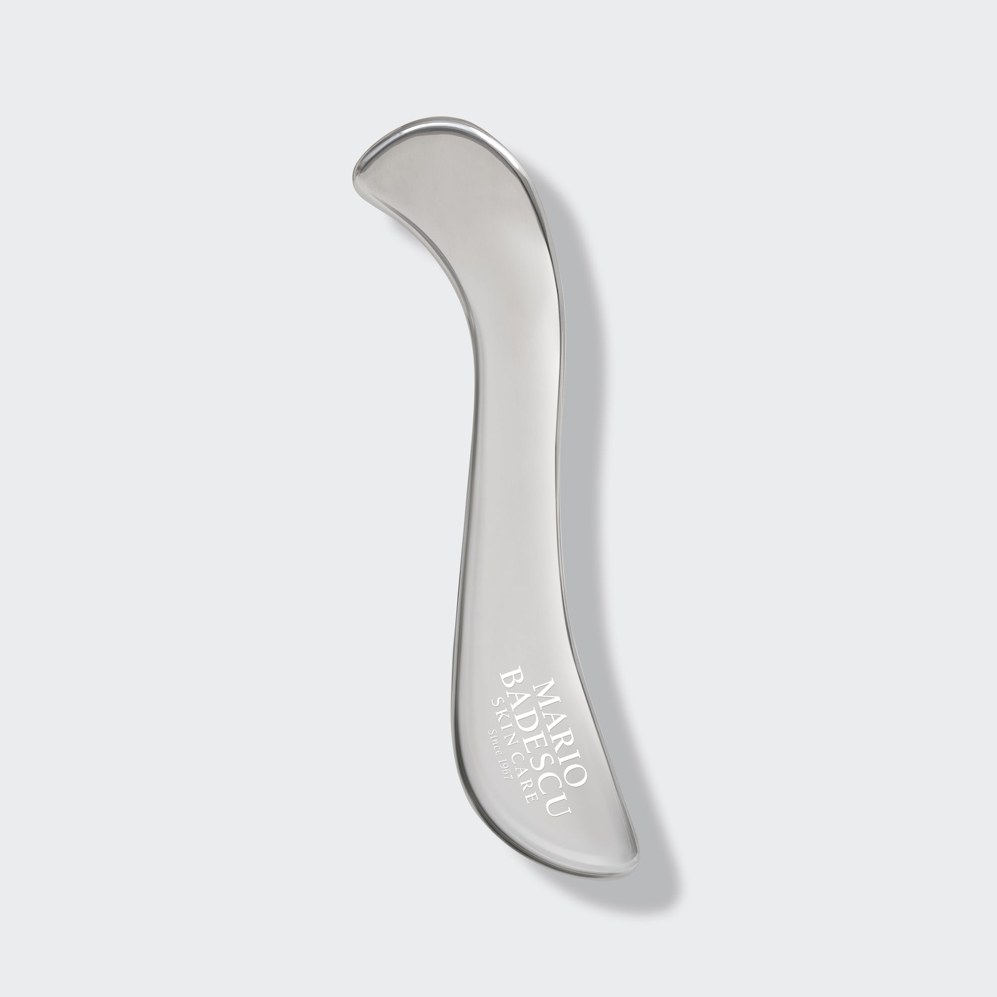 Silver facial roller with 'Mario Badescu' branding on a light gray background