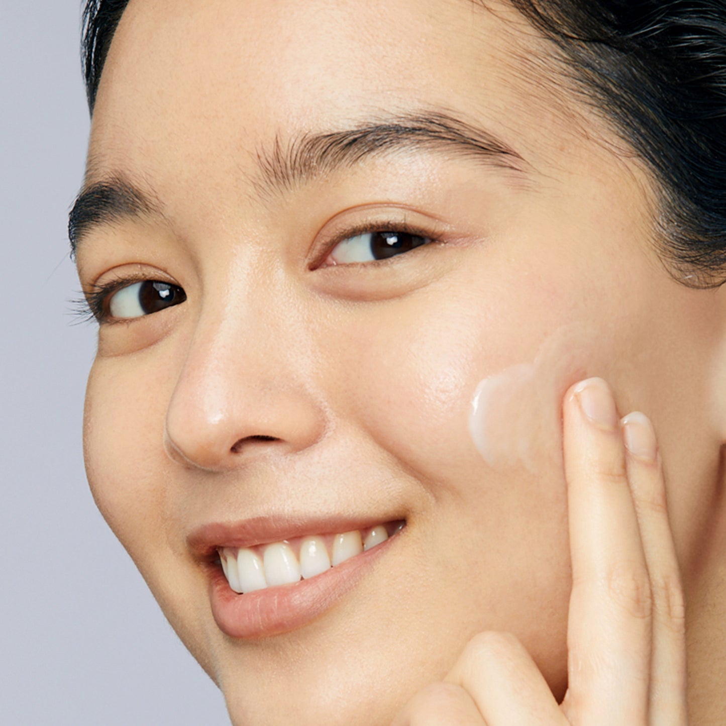 Woman with dewy skin demonstrating how to apply Hyaluronic Dew Cream