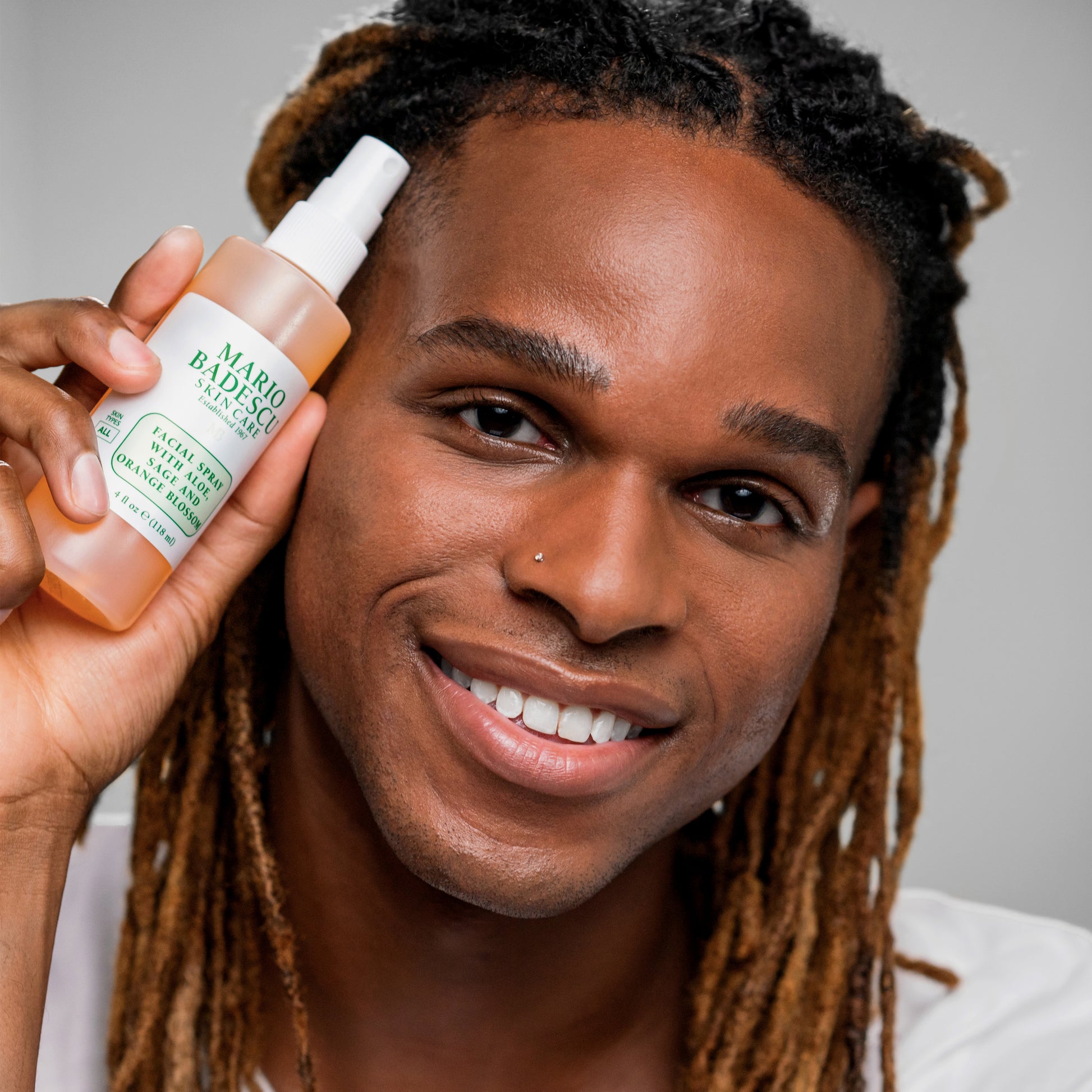 Man with glowing skin holding Facial Spray With Aloe, Sage, Orange Blossom