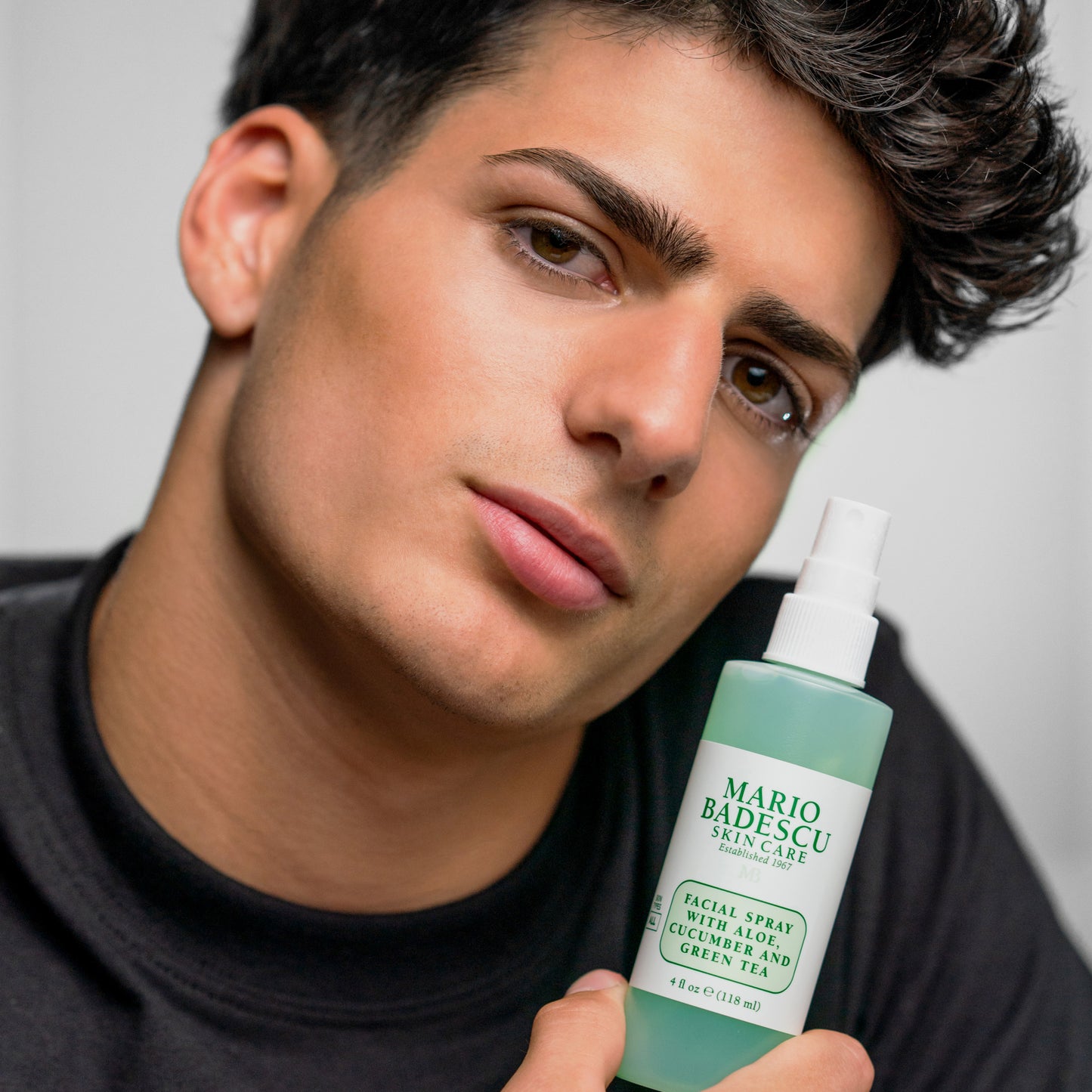 Man with glowing skin holding Facial Spray With Aloe, Cucumber, Green Tea