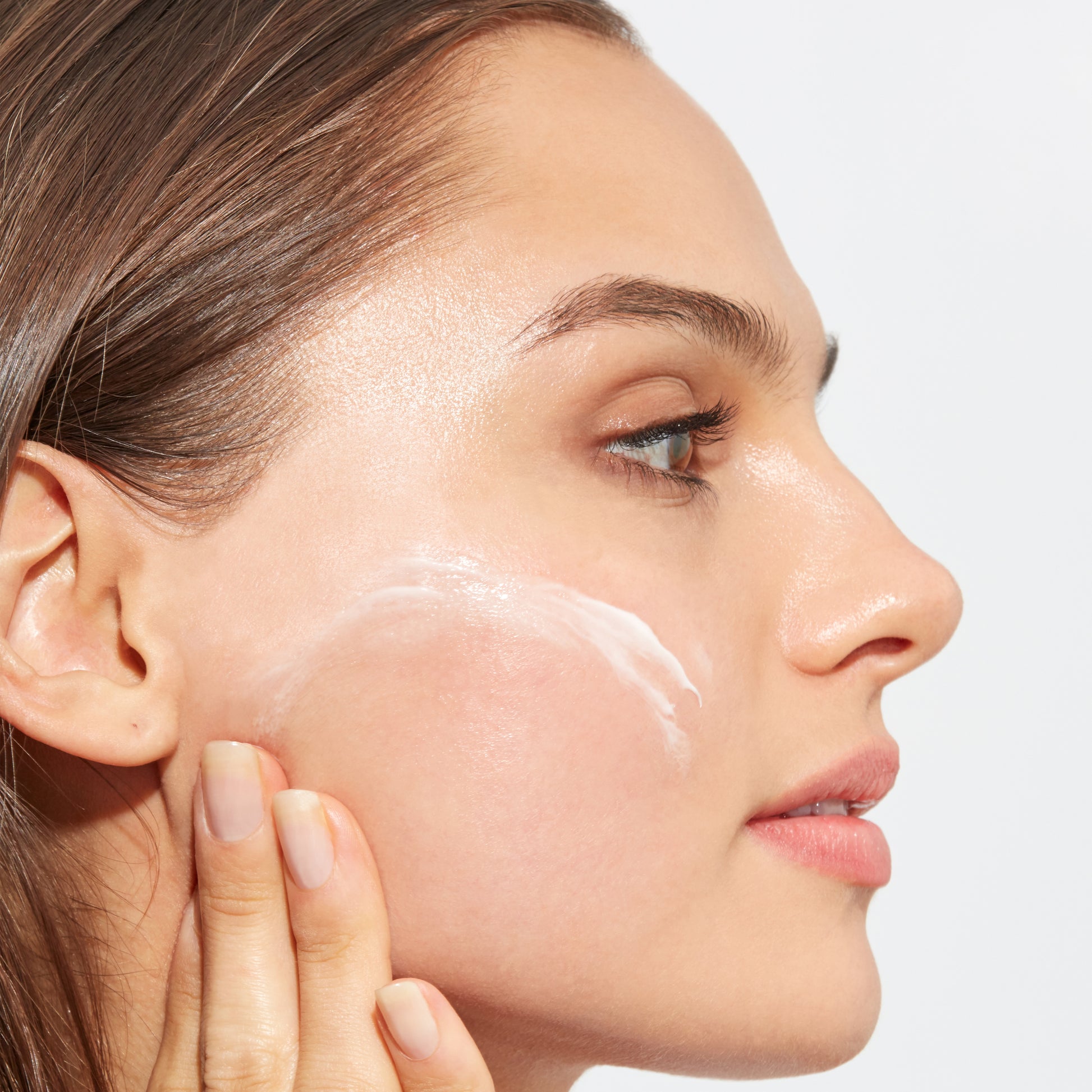 Woman with bright and even skin demonstrating how to apply Vitamin C Cream